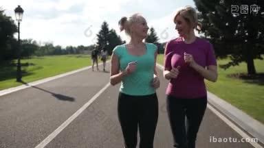 两个微笑的运动高级妇女在公园里<strong>跑步</strong>在一个阳光明媚的日子美丽的成年金发女<strong>跑步</strong>者在户外慢跑
